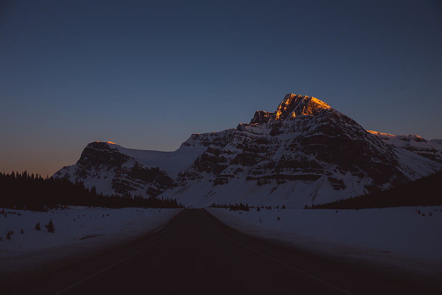 Snowy Mountain Road at Sunset with Golden Peak