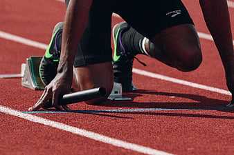 Relay runner in starting blocks holding baton on track