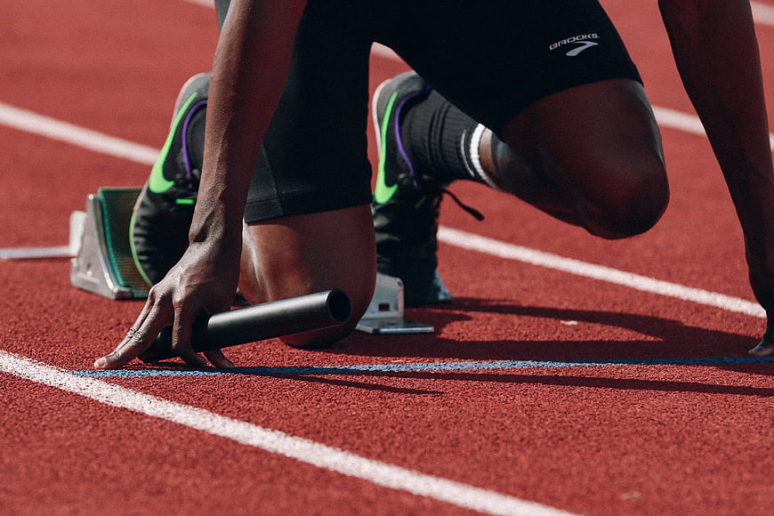 Relay runner in starting blocks holding baton on track
