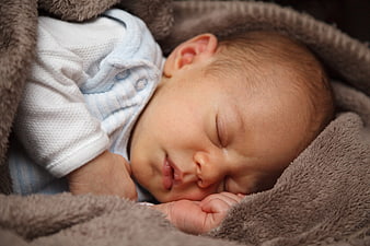 Close-up of a sleeping newborn baby wrapped in a brown blanket