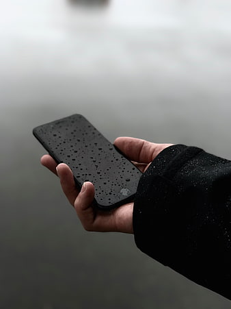 Hand holding wet smartphone in rain