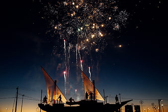 Silhouetted Sailboat with Fireworks Display at Night