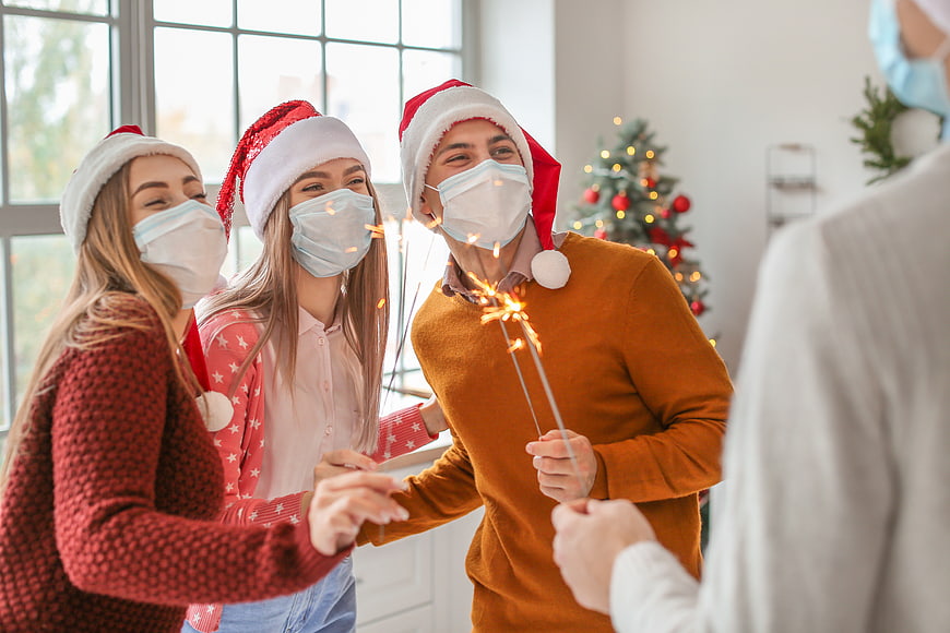Friends celebrating Christmas with sparklers and face masks