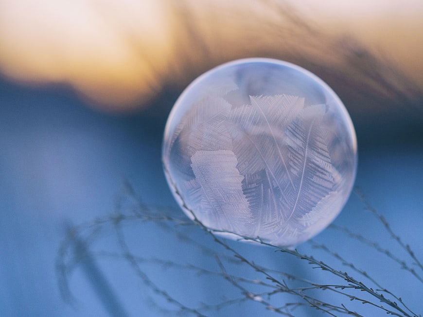 Frosted glass sphere with feather pattern on blue background