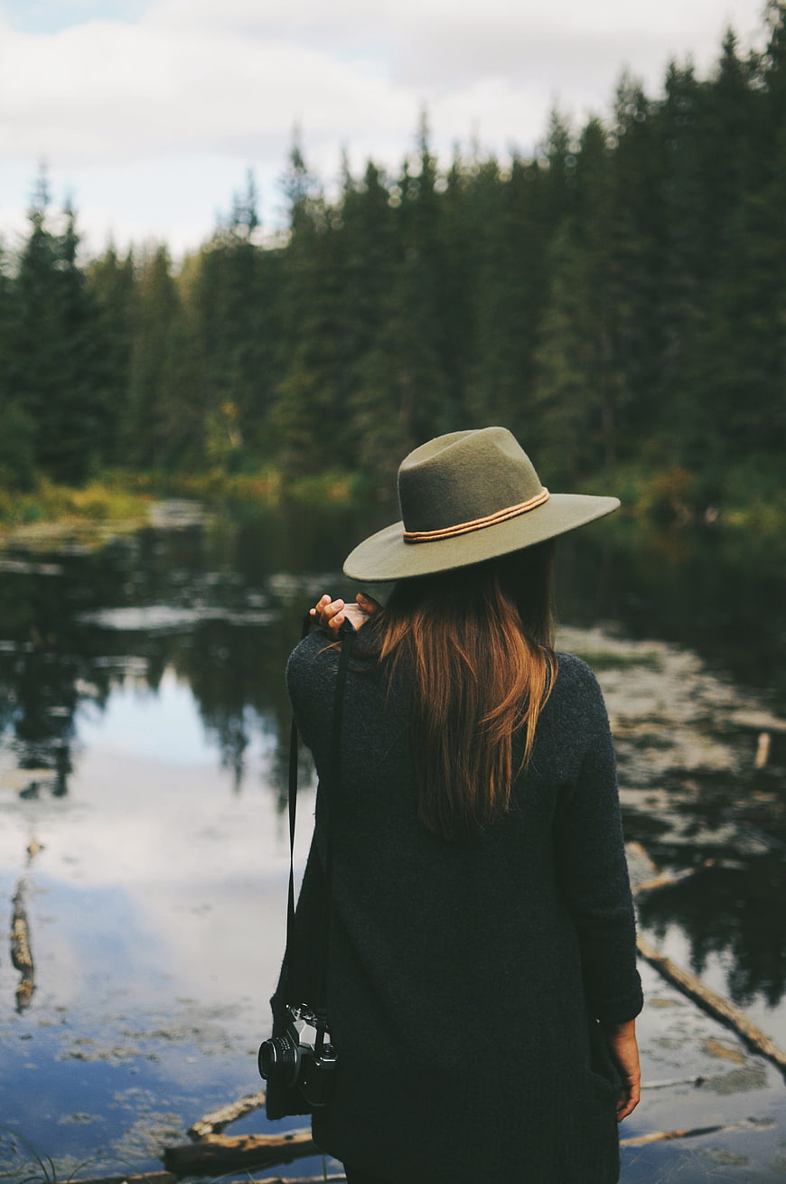 Woman with Camera Standing by Lake in Forest