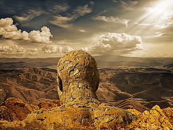 Stone Head Sculpture Overlooking Dramatic Mountain Landscape