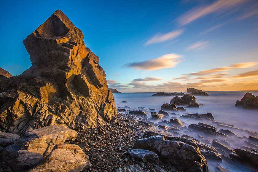 Dramatic coastal rock formation at sunset with long exposure ocean