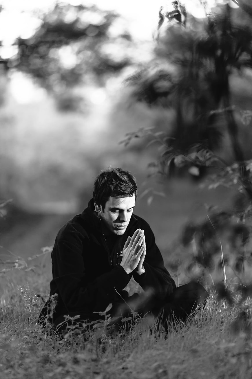 Black and white portrait of man praying in nature