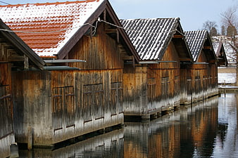 Traditional wooden boathouses with snow-covered roofs on a canal