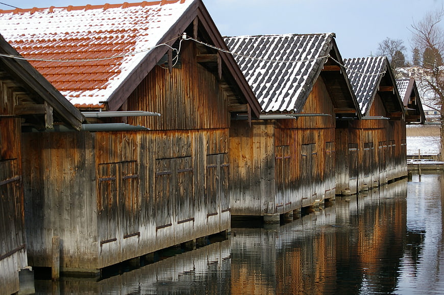 Traditional wooden boathouses with snow-covered roofs on a canal
