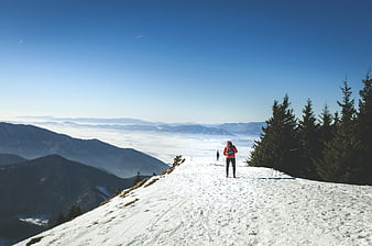 Hiker on Snowy Mountain Ridge Overlooking Sea of Fog