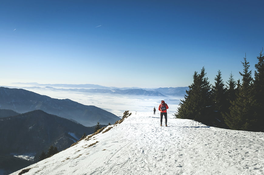 Hiker on Snowy Mountain Ridge Overlooking Sea of Fog