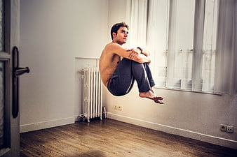 Shirtless Man Floating in Meditation Pose in Minimalist Room