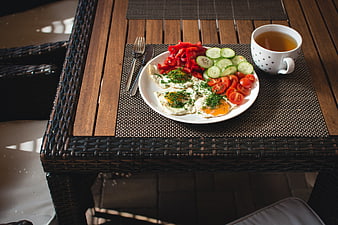 Healthy breakfast with fried eggs, fresh vegetables, and tea on a wooden table