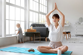 Mother practicing yoga at home with toddler playing nearby