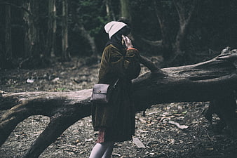 Woman in forest leaning on fallen log