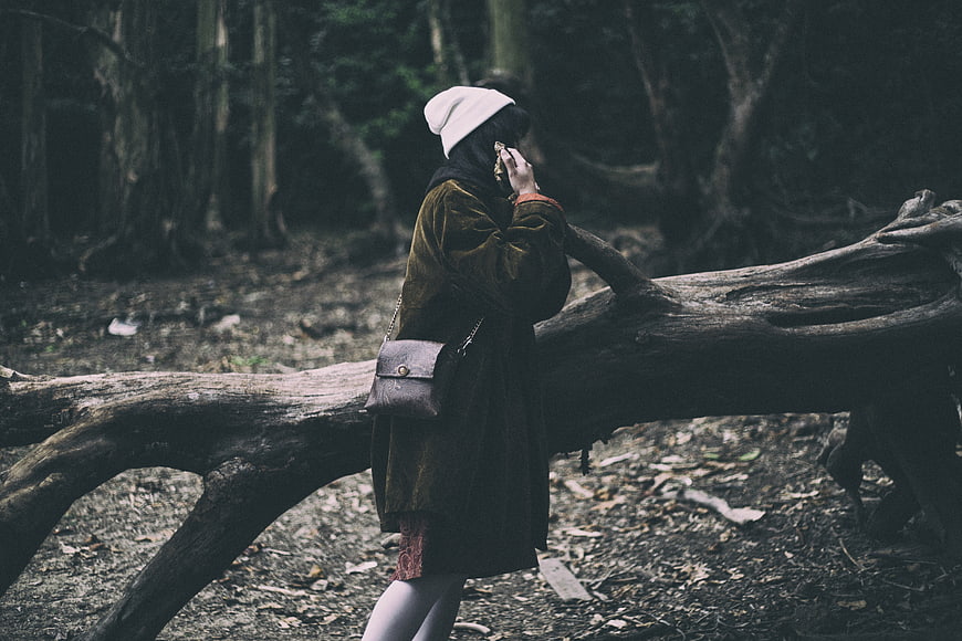 Woman in forest leaning on fallen log