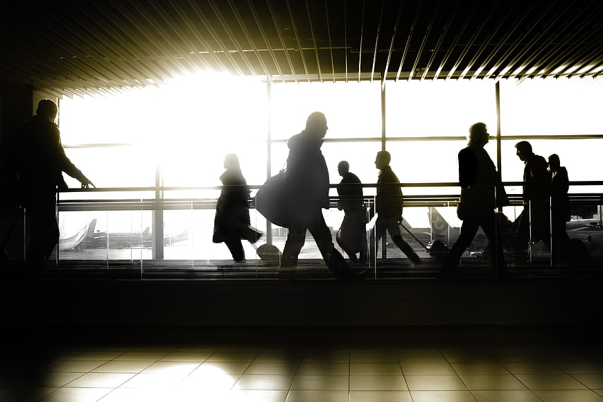 Silhouettes of travelers walking through airport terminal