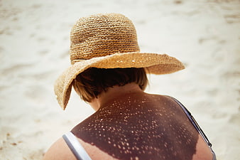 Woman in Straw Hat with Sunlight Shadows on Beach