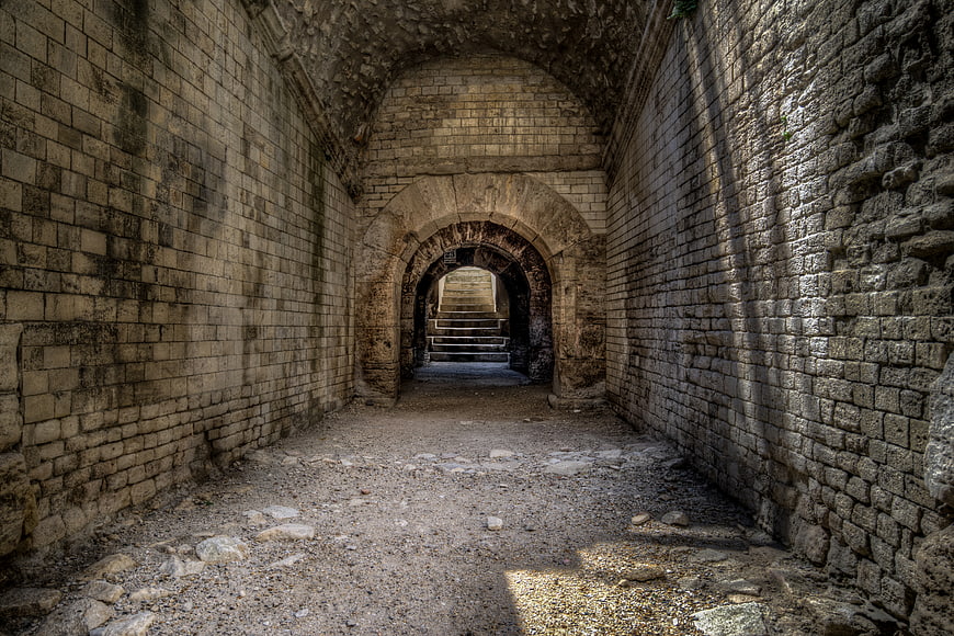 Ancient stone tunnel with arched passageway and textured walls