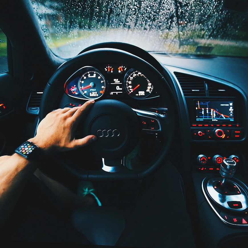 Hand on Audi steering wheel driving in rain