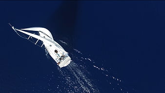 Aerial view of white sailboat on deep blue ocean