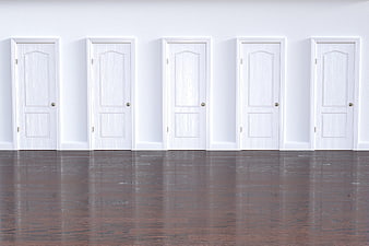 Five white doors in a row on a white wall with dark floor