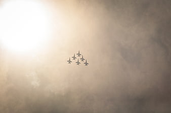 Formation of fighter jets flying through hazy clouds