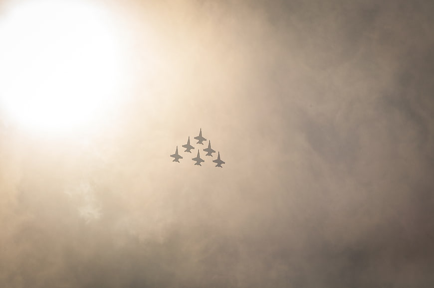 Formation of fighter jets flying through hazy clouds