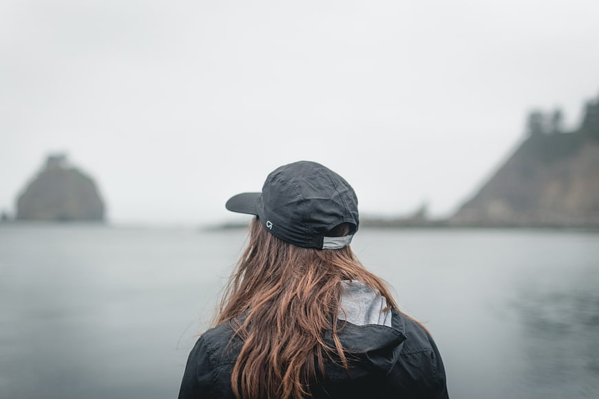 Woman in Black Cap Looking at Ocean Coastline