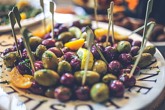 Gourmet marinated olives with lemon wedges on a white plate