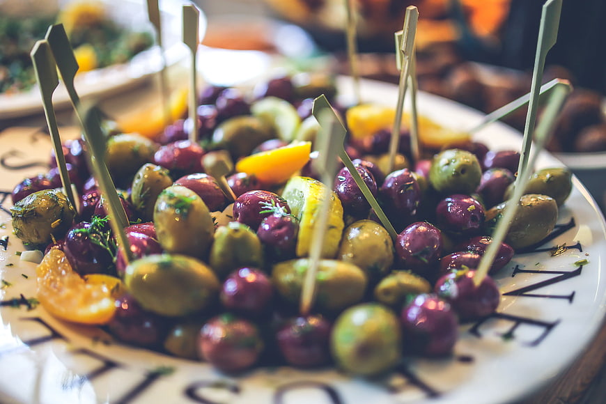 Gourmet marinated olives with lemon wedges on a white plate