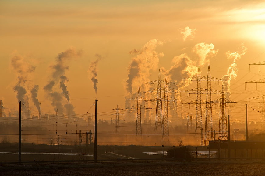 Industrial smokestacks and power lines at golden hour sunset