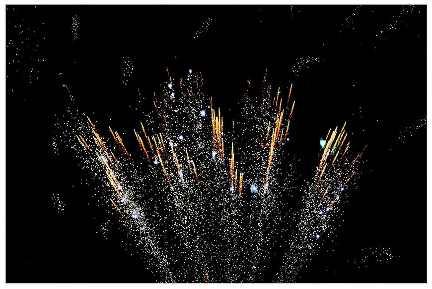 Golden fireworks exploding in the night sky