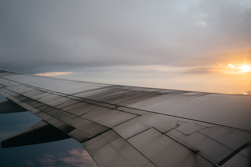 Airplane Wing View at Sunset with Clouds
