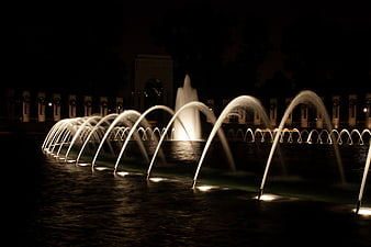 Illuminated water fountain jets at night in a dark park