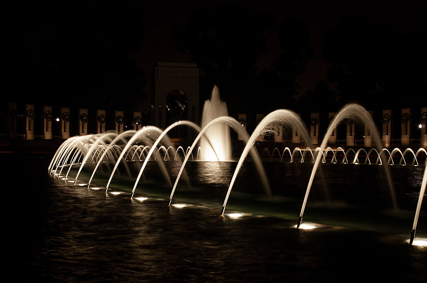 Illuminated water fountain jets at night in a dark park