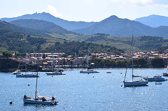 Sailboats in Mediterranean Harbor with Coastal Town and Mountains
