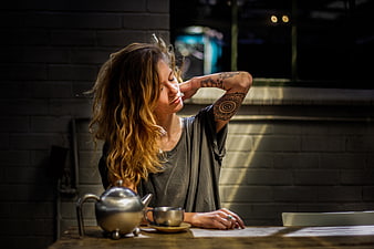 Woman with tattoos relaxing with tea in a cafe