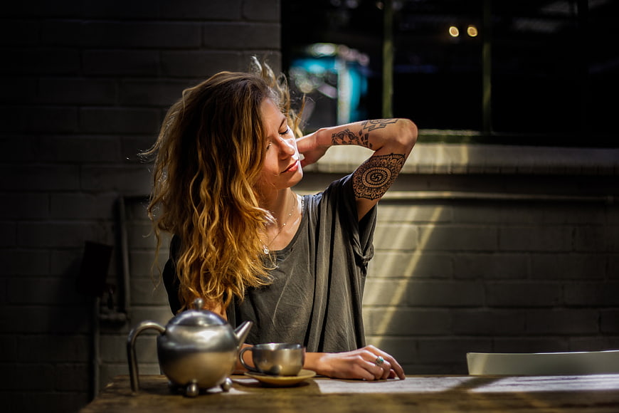 Woman with tattoos relaxing with tea in a cafe