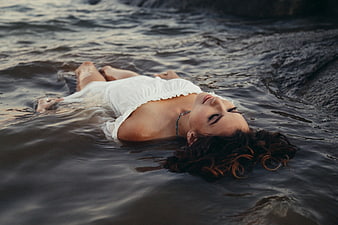 Woman floating in ocean water wearing white dress