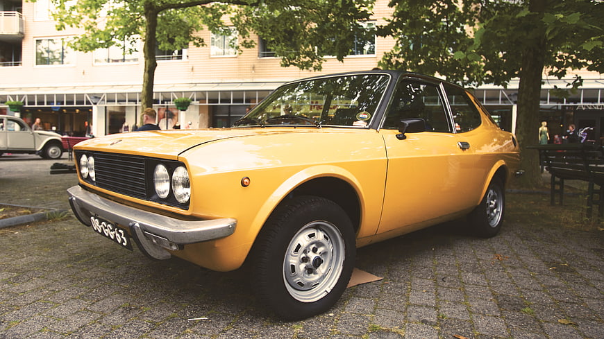 Yellow vintage classic car parked on cobblestone street