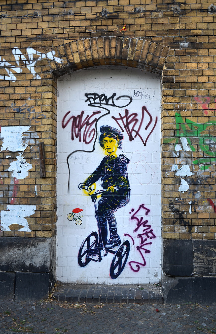Street Art Mural of Boy on Scooter on Brick Wall