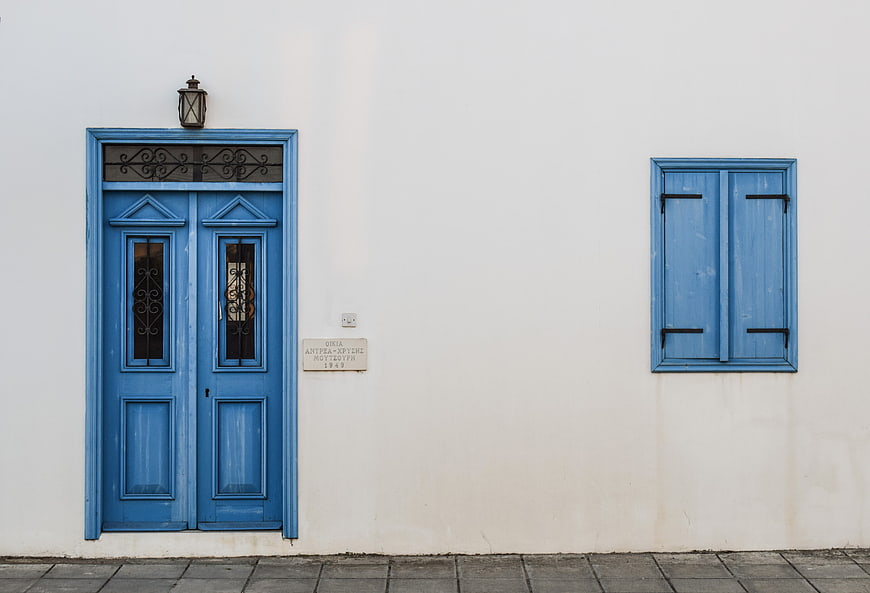 Blue wooden door and window on white wall in Cyprus