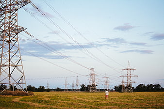 Man Standing in Field Under High Voltage Power Lines