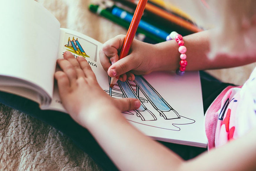 Child Coloring in Book with Pencil