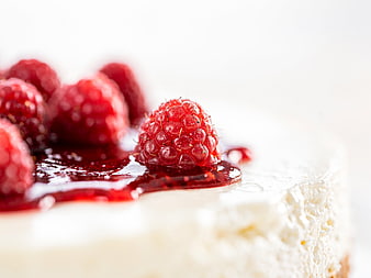 Close-up of creamy cheesecake with fresh raspberries and red glaze