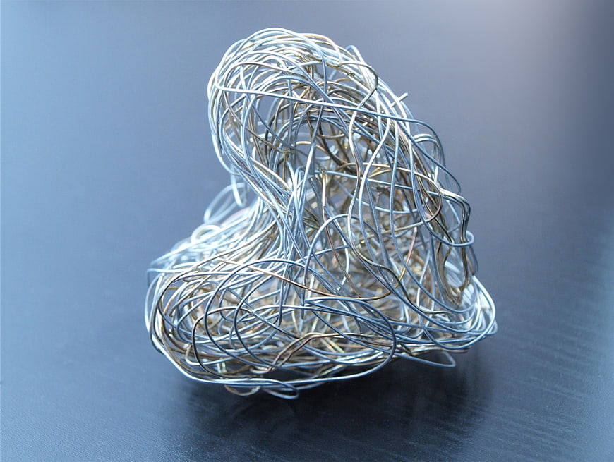 Silver Wire Sculpture Forming Heart Shape On Dark Surface