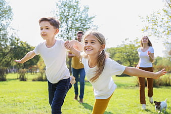 Happy family running together in a sunny park with dog