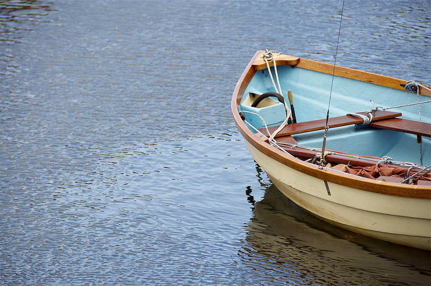 Small wooden boat with blue interior on calm water